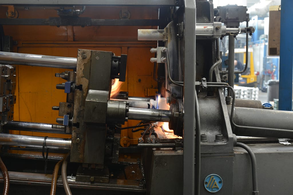 Interno pressa Agrati Z25 durante fusione con fiamma visibile e zama fusa nel pistone iniezione. - Micrometal