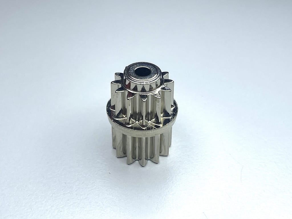 Ingranaggio/pignone a denti dritti pressofuso in zama nichelato lucido, singolo pezzo su sfondo chiaro. - Micrometal